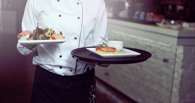 Image of a chef carrying plates of food
